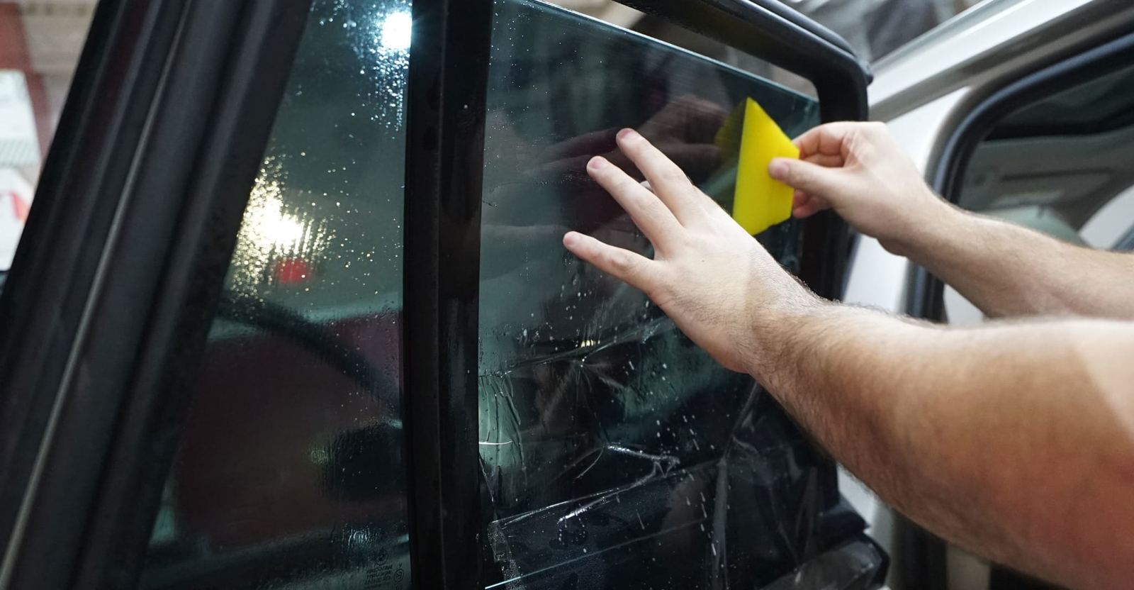 Hand applying window tint film with a squeegee
