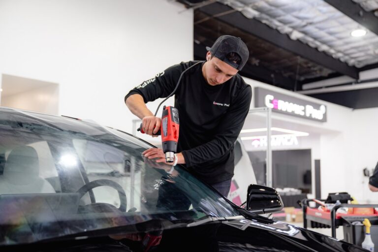 Technician installing car window tint film on a vehicle windshield at IMS Detailing in Hooksett, NH