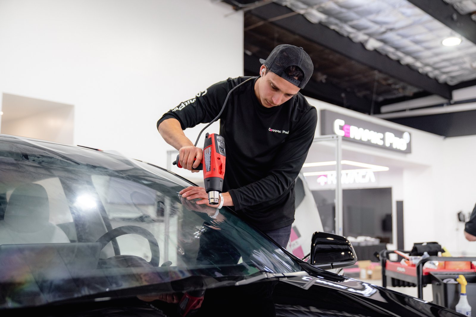 Technician installing car window tint film on a vehicle windshield at IMS Detailing in Hooksett, NH
