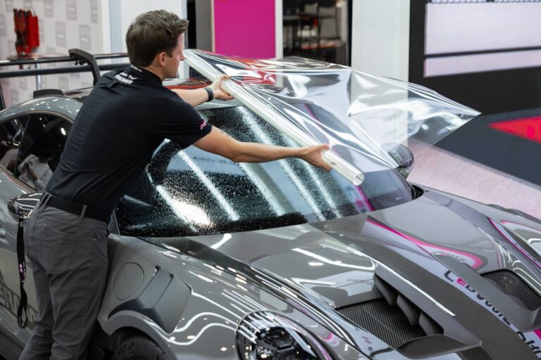 Installer applying clear paint protection film to a sports car hood at IMS Detailing in Hooksett, NH