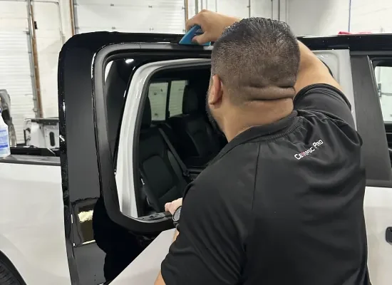 window-tint-install-hooksett-nh Installer applying window tint to a white SUV rear door window